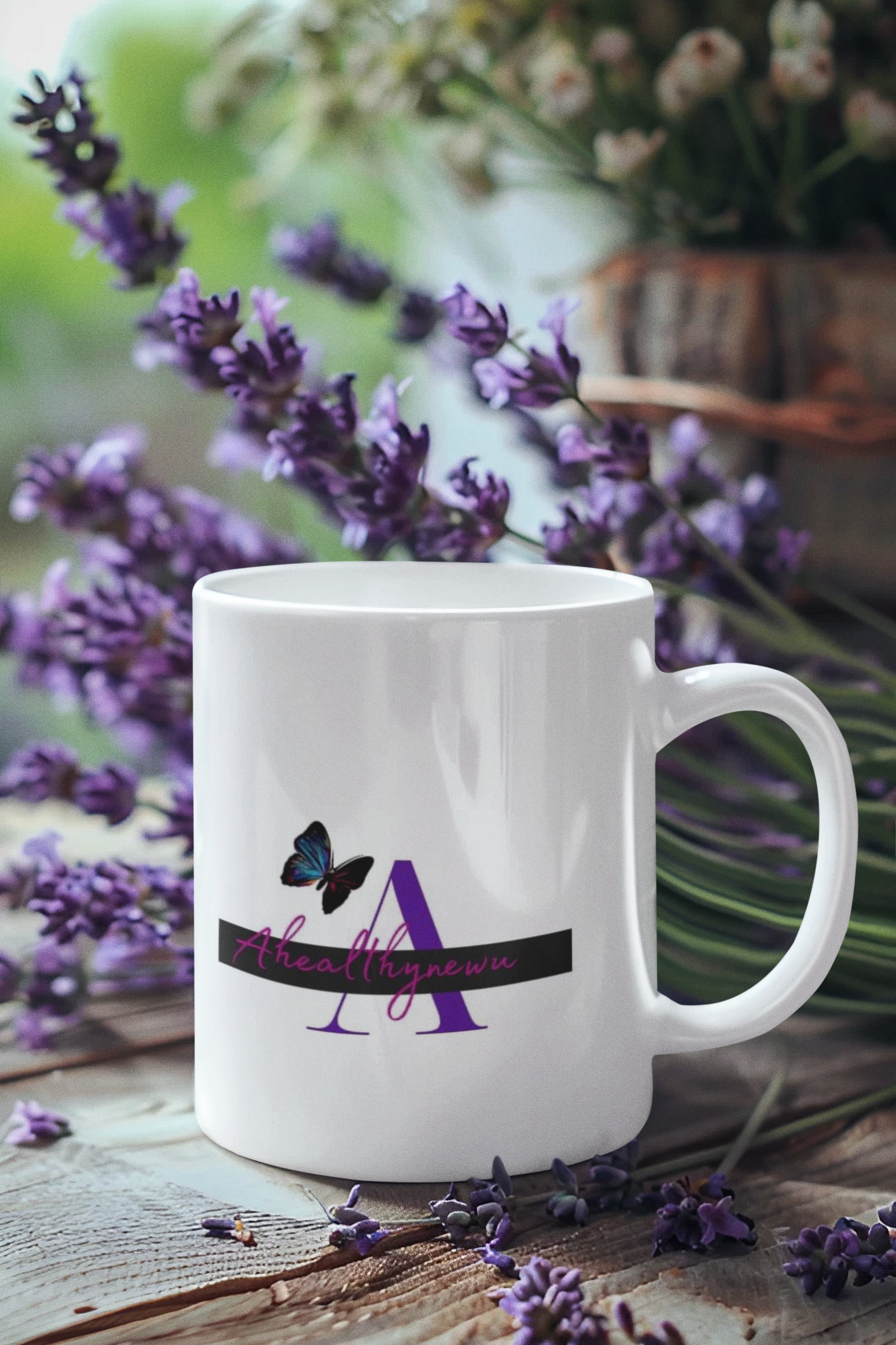 White mug with a purple 'A' and butterfly logo, surrounded by lavender on weathered wood.
